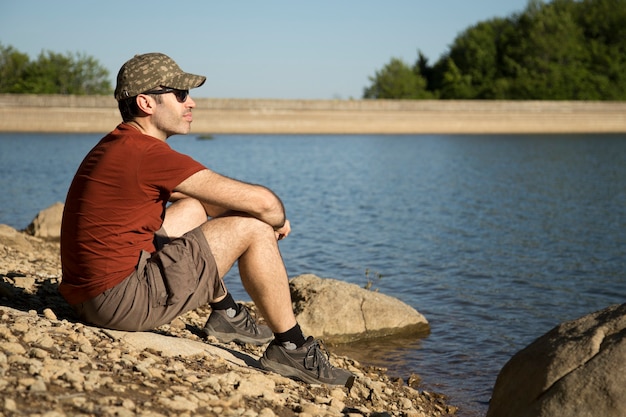 Escursionista che prende il sole al tramonto sulla riva di un lago