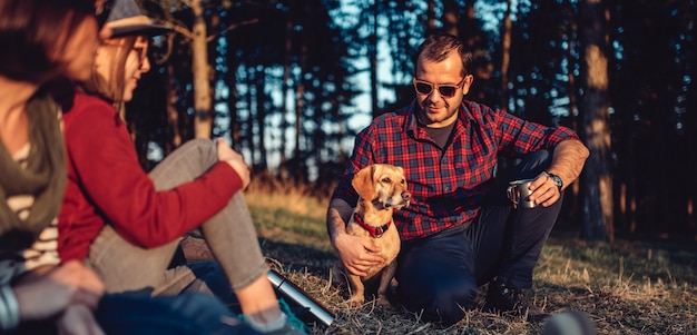 Escursionista con gli amici e il suo cane a riposo e bere caffè