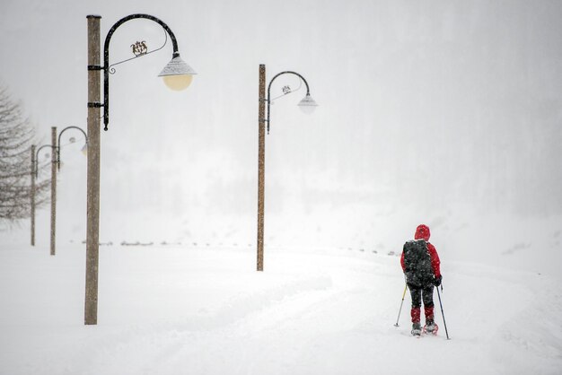 Escursionista con racchette da neve isolato mentre nevicava