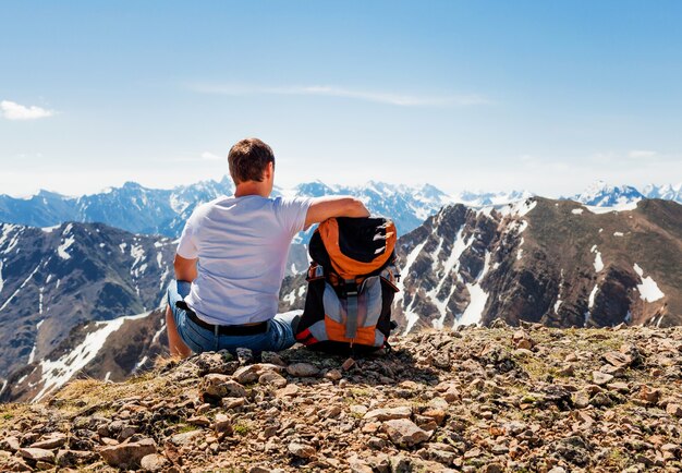 Escursionista con zaino seduto in cima a una montagna, montagne e coste in viaggio, libertà e concetto di stile di vita attivo.