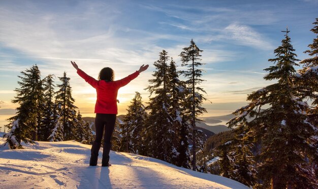 Escursionista donna adulta sulla cima della montagna di Hollyburn al tramonto della stagione invernale