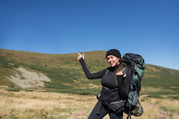 Escursionista donna si trova sulla cima della montagna, il dito indice della mano indica lo spazio vuoto