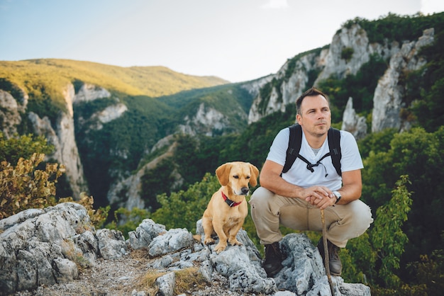 Escursionista e il suo cane seduto sulla cima della montagna