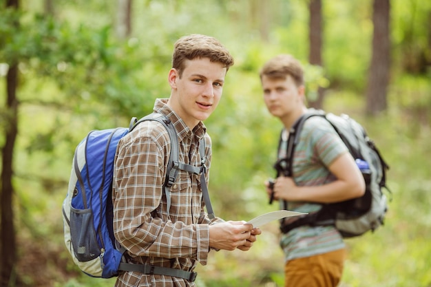 Escursionista in piedi nel bosco con un amico e guardando la telecamera