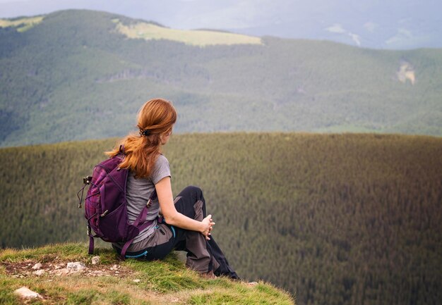 Escursionista ragazza con uno zaino seduto sullo sfondo di montagne e foreste. Vorokhta - Paesaggio ucraino.