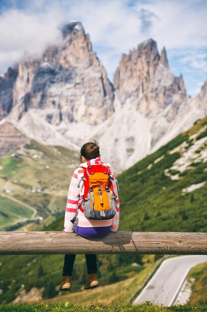 Escursionista ragazza seduta e guardando le montagne innevate. Dolomiti, Italia.