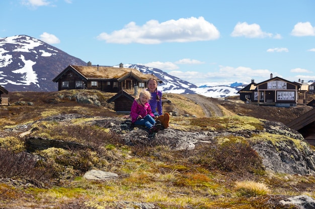 Escursionista ragazza seduta su uno sfondo di vecchie case di legno tradizionali a Tyin, Norvegia