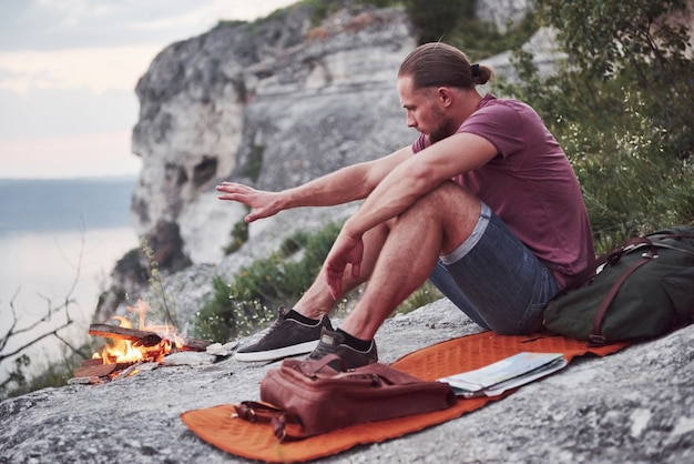 Escursionista uomo di successo in cima alla roccia con falò. libertà e concetto di stile di vita attivo