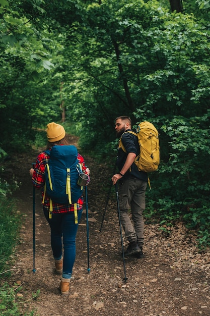 Escursionisti che utilizzano bastoncini da trekking mentre indossano zaini con attrezzatura da campeggio