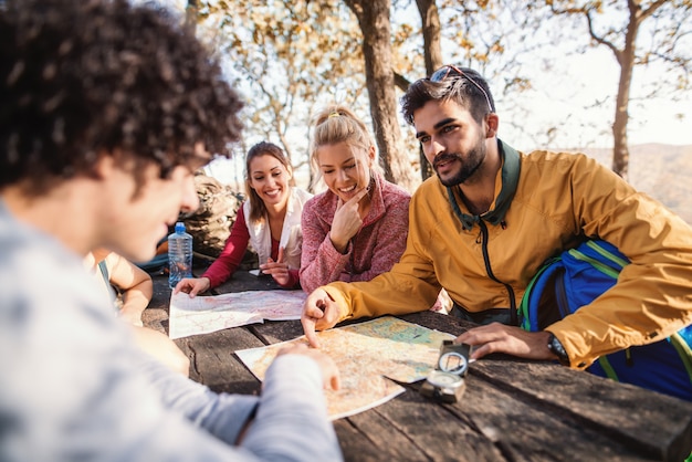 Escursionisti seduti sulla panchina al tavolo nel bosco e guardando la mappa