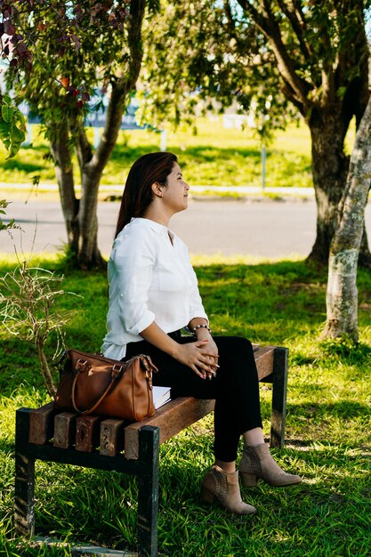 Esecutivo donna seduta in appoggio su una panchina nel parco