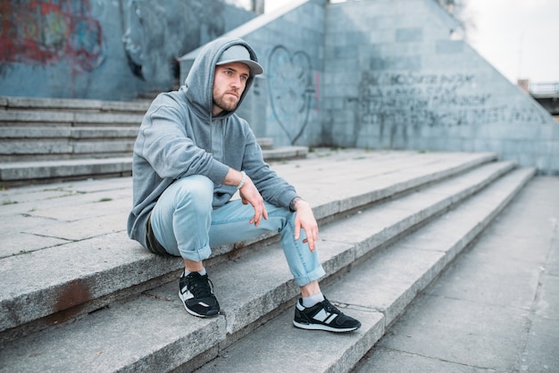 Esecutore di danza seduto sui gradini, stile di danza urbana, ballo di strada. Ballerino maschio