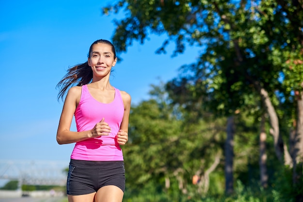 Esecuzione di donna. Corridore femminile che pareggia durante l'allenamento all'aperto in un parco. Bella ragazza in forma. Modello di fitness all'aperto. Perdita di peso