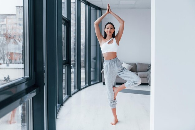 Esercizi di yoga La giovane donna con una forma del corpo snella in abbigliamento sportivo ha una giornata di fitness al chiuso a casa