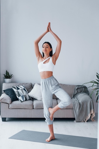 Esercizi di yoga La giovane donna con una forma del corpo snella in abbigliamento sportivo ha una giornata di fitness al chiuso a casa