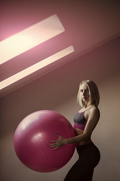 Esercizi per donne con la palla Atleta ragazza in abbigliamento sportivo con fitball rosa
