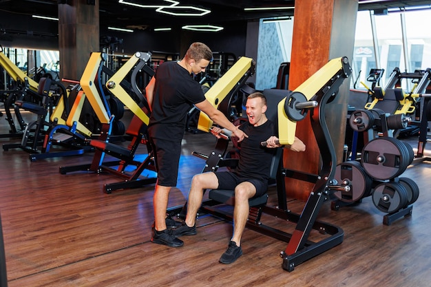 Esercizi sportivi per un uomo con un allenatore nella sala fitness, sport maschile.