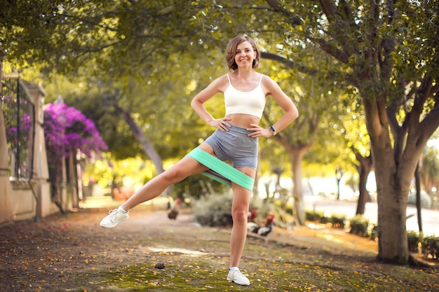 Esercizio con elastici fitness all'aperto. Addestramento della donna all'aperto. Concetto di fitness e assistenza sanitaria