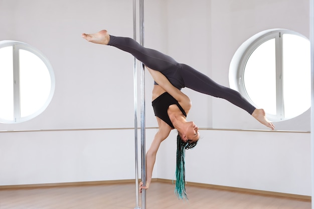 Esercizio di acrobazie con il palo per il fitness nella palestra dello studio di allenamento