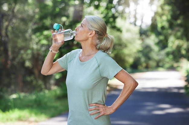 Esercizio di fitness e donna matura che beve acqua all'aperto e allenamento per l'equilibrio, aria fresca e pausa