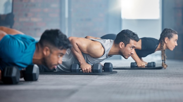 Esercizio di fitness e palestra con un personal trainer che insegna o allena un allenamento di classe in un centro benessere Allenatore di motivazione e manubri con un atleta uomo e un gruppo di studenti in una sessione per la forza