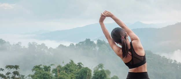 Esercizio donna atleta al mattino, giovane donna fitness che allunga i muscoli contro la vista sulle montagne, riscaldamento pronto per correre o fare jogging. Concetti di allenamento, benessere e sport girl