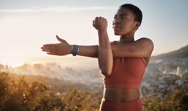 Esercizio fitness e donna nera che allunga il braccio all'aperto per la salute e il benessere Pensare all'allenamento sportivo e alla preparazione femminile per riscaldarsi e prepararsi per l'allenamento cardio o correre al tramonto