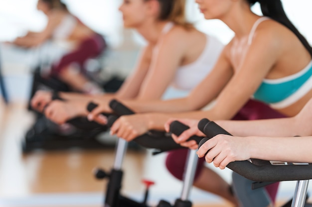 Esercizio su bici da palestra. Immagine ritagliata di un albero di giovani donne in abbigliamento sportivo