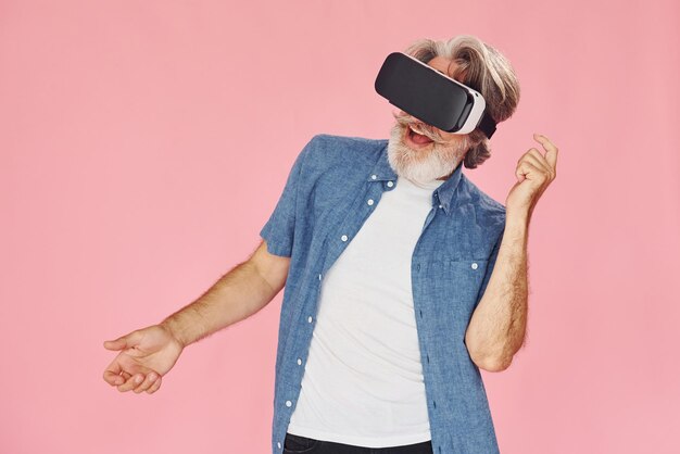 Esperienza di realtà virtuale L'uomo anziano moderno ed elegante con i capelli grigi e la barba è al chiuso