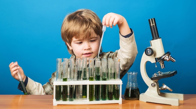 Esperimento educativo ragazzo con provette e microscopio nel bambino del giorno della conoscenza dell'aula scolastica