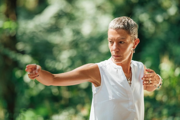 Esperto femminile di Qi Gong che fa esercizi di Qigong all'aperto per spostare Chi o energia nel corpo