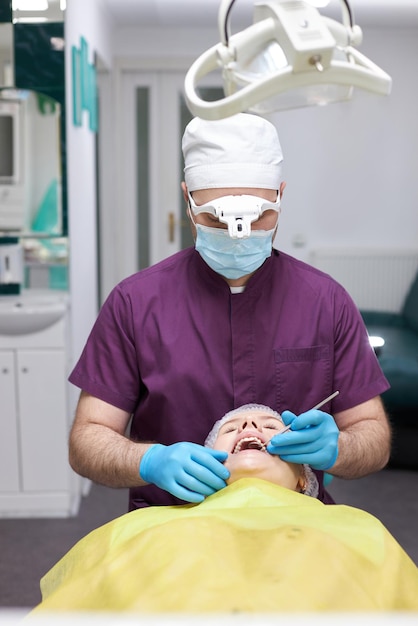 Esperto igienista dentista che utilizza la sonda dentale dentale controlla i denti della donna in una clinica odontoiatrica