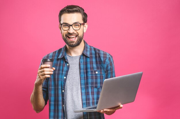 Esperto in affari sicuri. Giovane uomo bello sicuro con caffè nel computer portatile e nel sorridere della tenuta della camicia