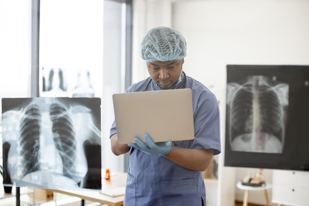 Esperto medico che utilizza il computer portatile durante l'analisi delle scansioni del torace