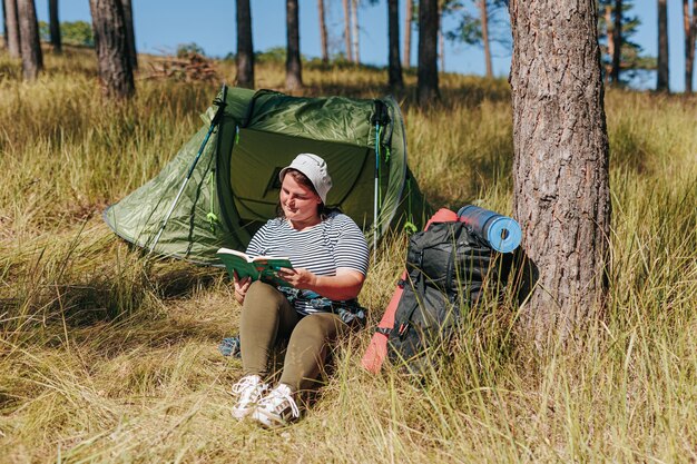 Esplora la bellezza della natura con una donna in sovrappeso che si riposa nel bosco per leggere un