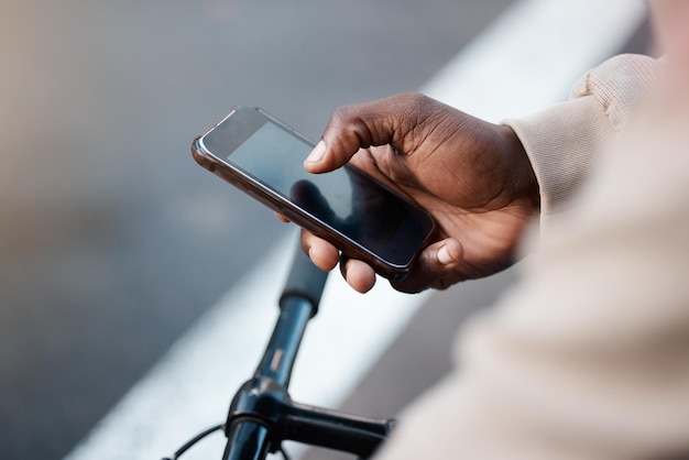 Esplorare la città in modo intelligente. Inquadratura di un uomo d'affari che usa il suo smartphone mentre va in bicicletta.