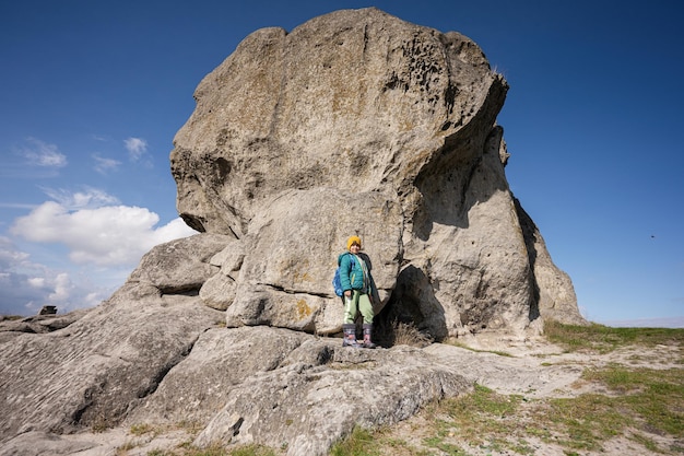 Esplorare la natura Il ragazzo indossa lo zaino che fa un'escursione vicino alla grande pietra in collina Pidkamin Ucraina