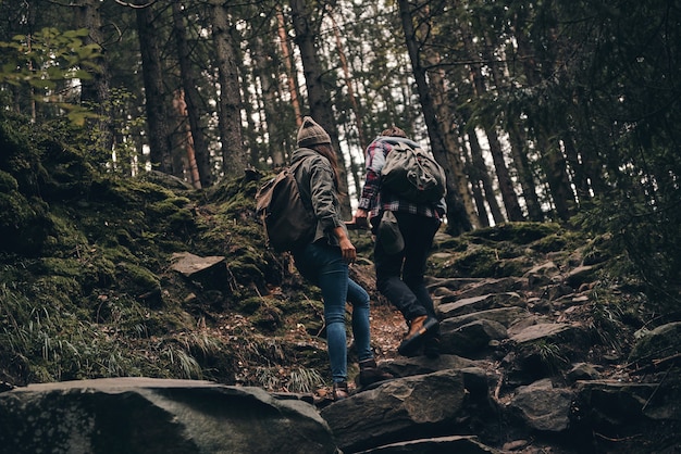 Esplorare la natura. Vista posteriore a tutta lunghezza di una giovane coppia che si alza durante un'escursione insieme nel bosco