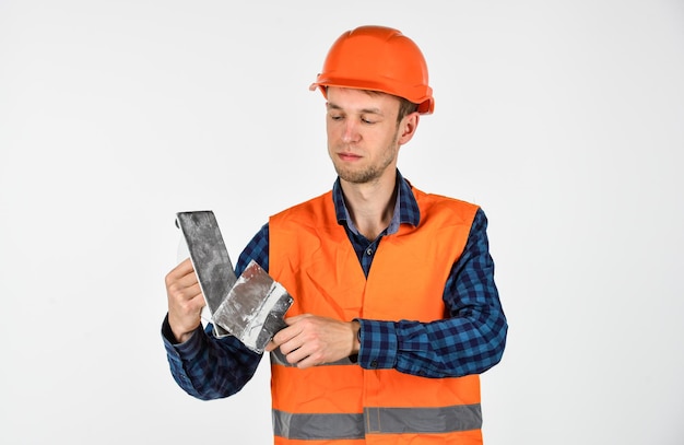 Esplorare strumenti costruzione strumento riparazione attrezzature giovane lavoratore è assistente tecnico riparatore in uniforme uomo uso spatola strumento vero operaio edile in casco carpentiere pronto a lavorare