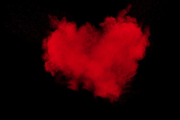 Esplosione astratta di polvere rossa su sfondo nero. Cuore rosso.