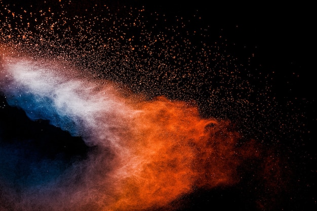 Esplosione di polvere blu arancione su sfondo nero. Nuvole di spruzzi di polvere di colore blu arancione.