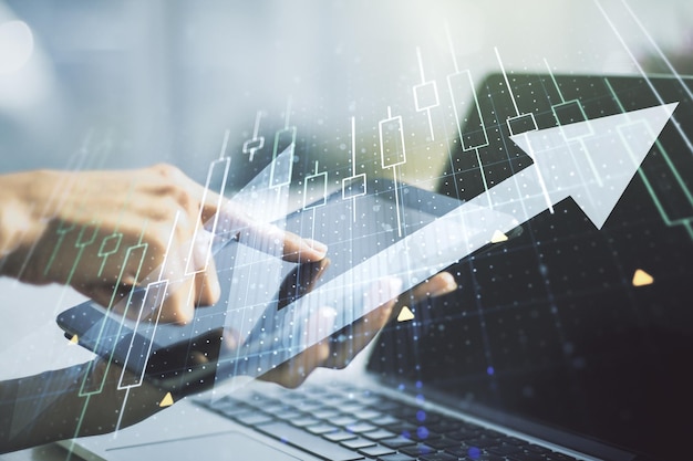 Esposizione multipla del diagramma finanziario astratto con freccia verso l'alto e mano che lavora con una tavoletta digitale su sfondo aumento e concetto rivoluzionario