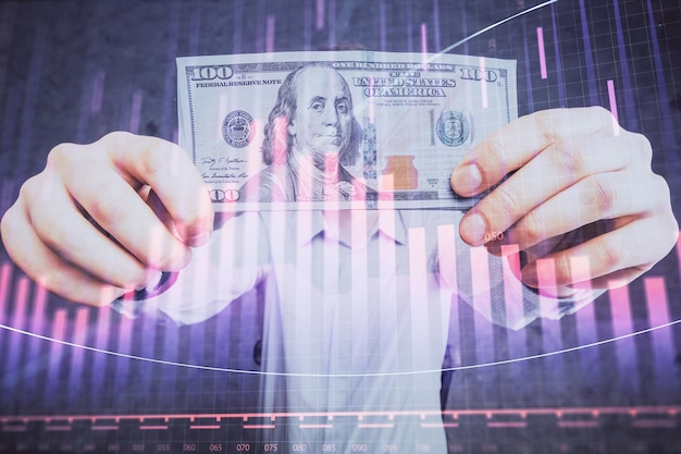 Esposizione multipla del grafico forex disegnando ologramma e banconote in dollari statunitensi e mani di uomo Concetto di analisi tecnica