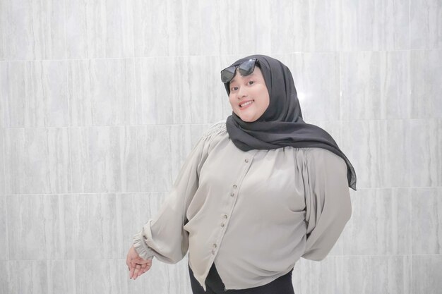 Espressione di una sorridente donna asiatica indonesiana che indossa un hijab e una camicia bianca