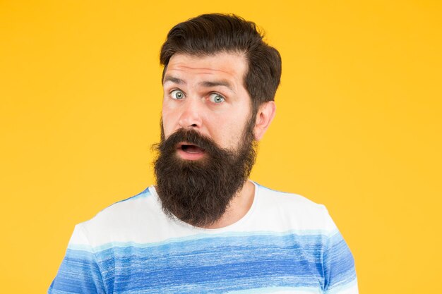 Espressione dubbiosa Faccia astuta Idea interessante Ragazzo che pensa Nella sua mente Un'altra idea Avere qualche dubbio Faccia con la barba hipster non sicura Uomo con la barba dubbiosa su sfondo giallo da vicino