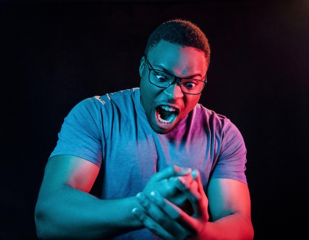Espressione facciale Illuminazione futuristica al neon Giovane uomo afroamericano in studio