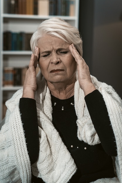 Espressiva bionda anziana sente mal di testa da stress