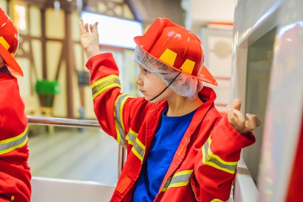 Espressivo bambino carino con vestito da vigile del fuoco che gioca a vigile del fuoco