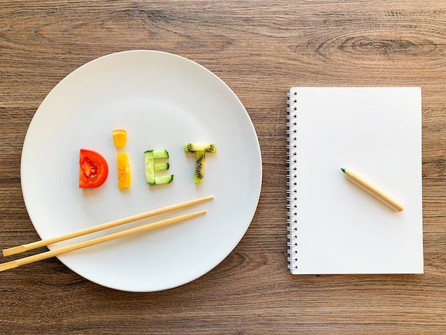 Esprima la DIETA fatta delle verdure affettate in piatto bianco e nel piano di dieta su legno