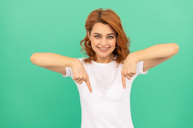 Esprimi emozioni positive guarda qui donna felice con i capelli ricci che punta il dito verso il basso